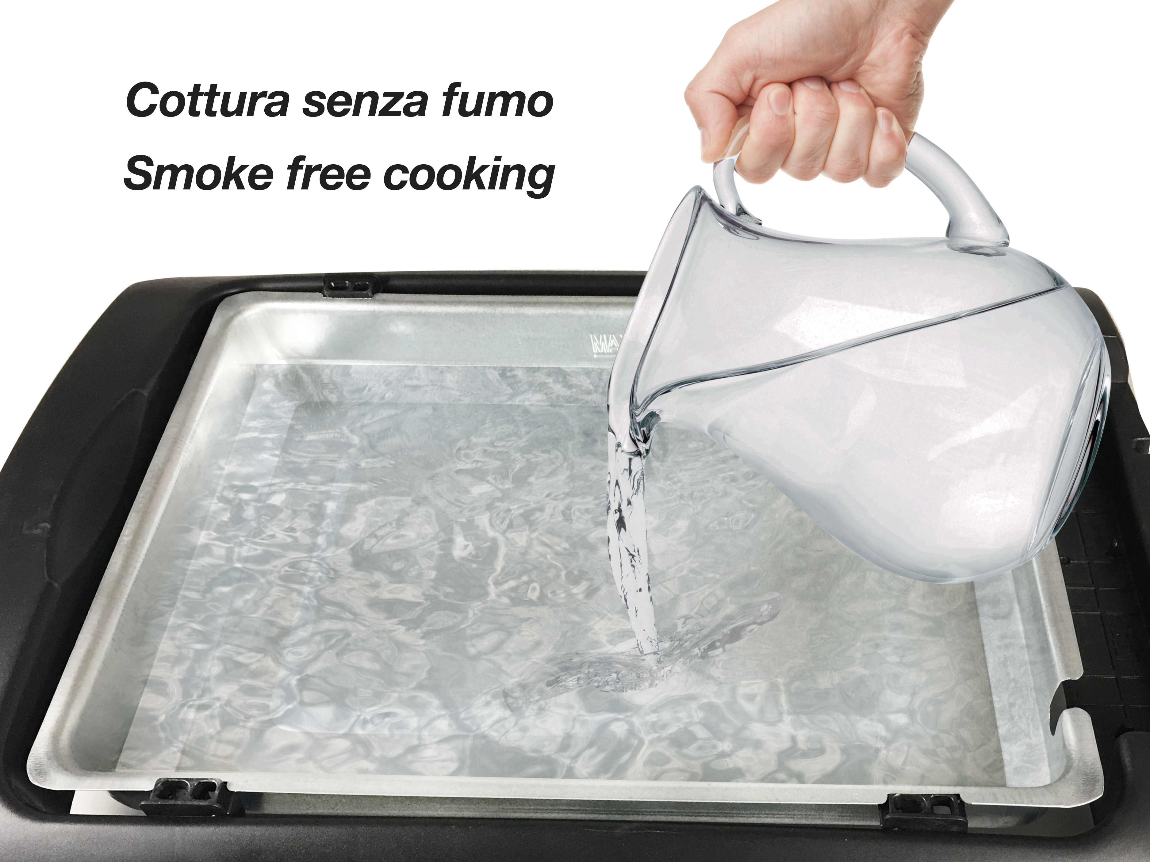 Ręka wlewa wodę z przezroczystego dzbanka do metalowej tacy. Tekst po włosku: Gotowanie bez dymu.