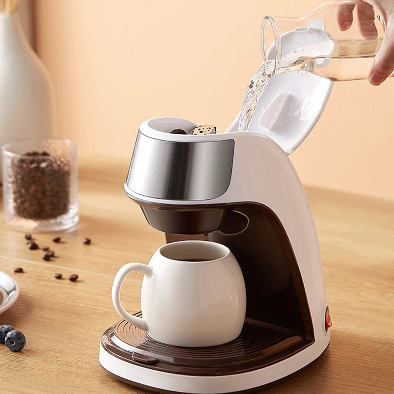 Kaffeemaschine, die Kaffee brüht. Wasser wird gegossen. Weiße Tasse. Kaffeebohnen und Vase im Hintergrund.