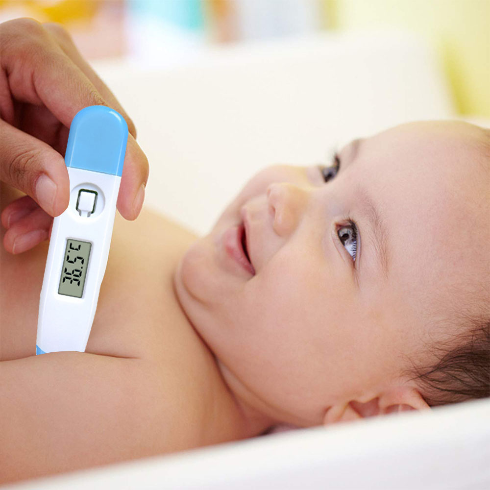 Eine Hand hält ein blau-weißes Thermometer in der Nähe der Brust eines Babys. Das Thermometer zeigt 36,5 Grad an. Das Baby lächelt und schaut nach oben.