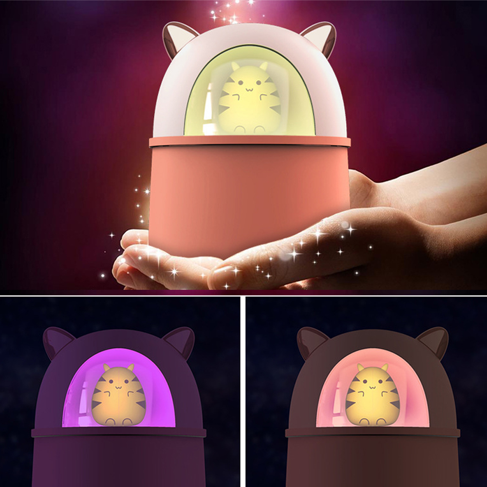 Eine Person hält eine katzenförmige Lampe. Die Lampe ist pfirsichfarben und weiß. Im Inneren befindet sich eine gelbe Katzenfigur. Der Hintergrund hat Glitzer.