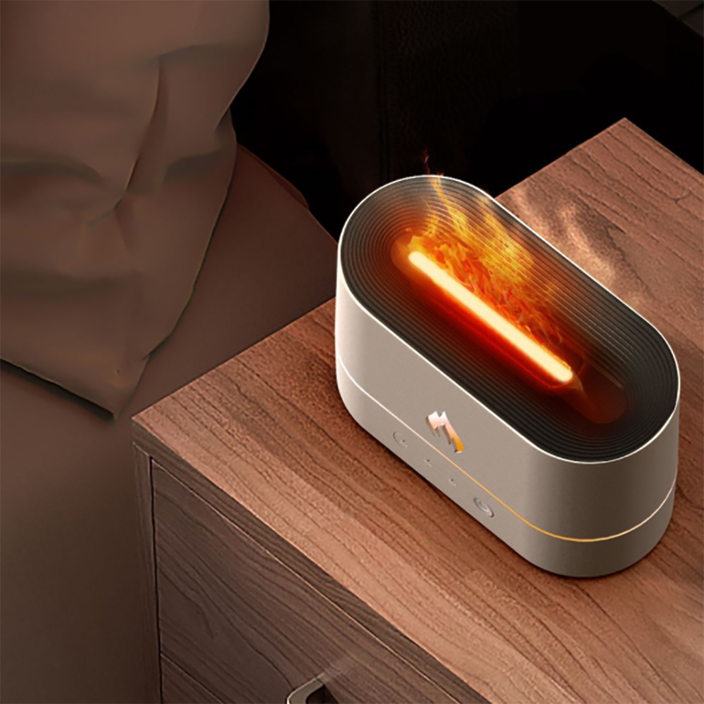 Ein modernes, ovales Nachtlicht mit Flammeneffekt. Es steht auf einem hölzernen Nachttisch neben einem Bett. Das Licht ist an.