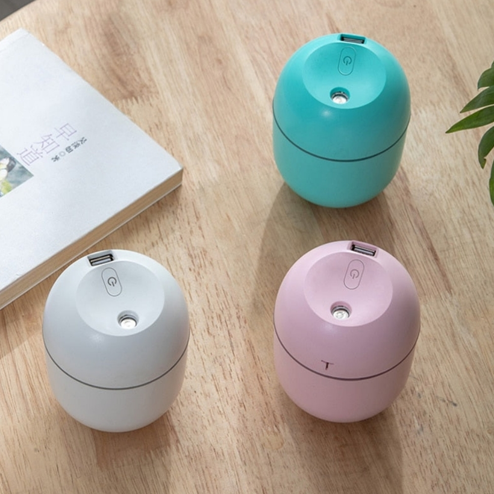 Drei farbige Diffusoren auf einem Holztisch. Links ist ein Buch. Die Farben sind weiß, türkis und rosa.