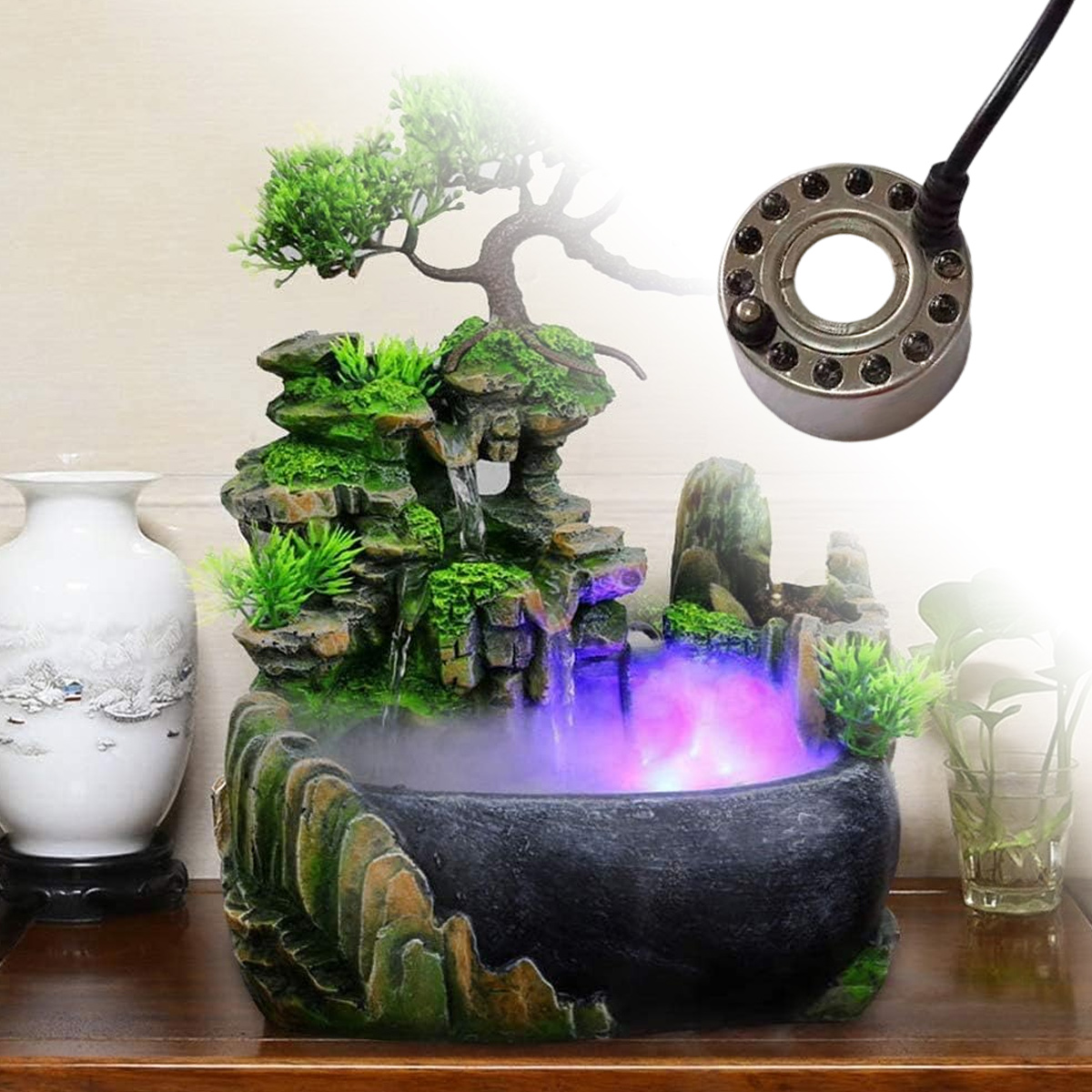 Ein dekorativer Tischbrunnen mit Miniaturbaum, Felsen und Wasserspiel, das Nebel abgibt. Eine LED-Leuchte ist ebenfalls enthalten.