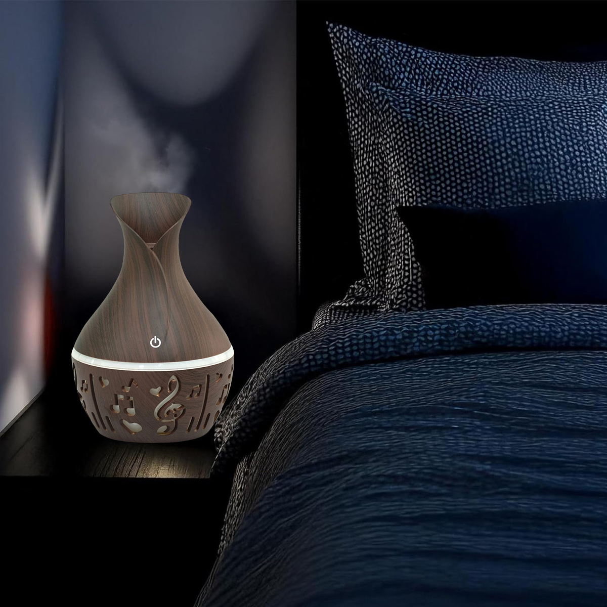 Ein dunkler hölzerner Diffusor für ätherische Öle auf einem Nachttisch, mit einem Bett im Hintergrund. Der Diffusor hat Noten-Ausschnitte und Dampf.