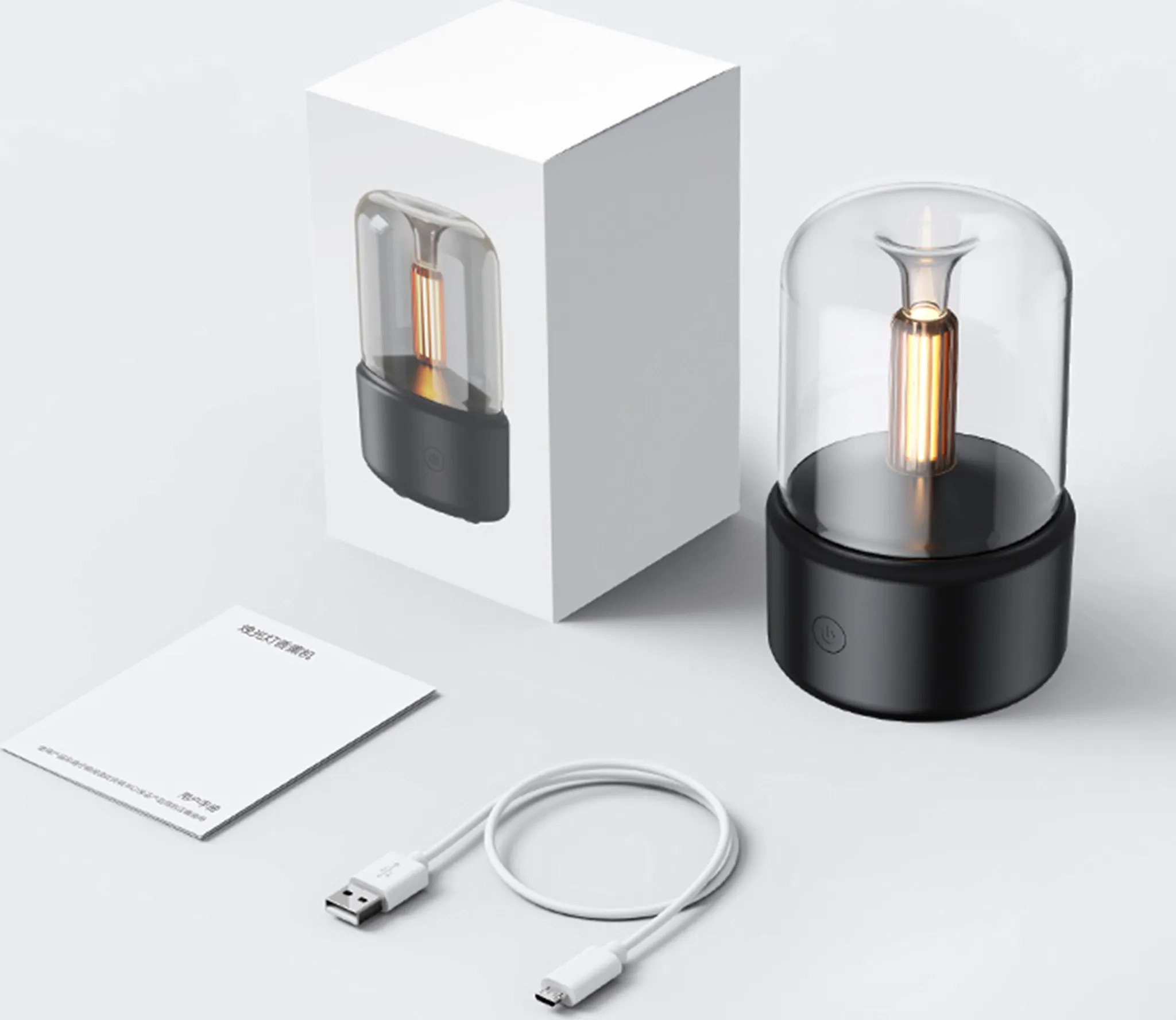 Eine moderne Lampe mit schwarzem Sockel und klarer Abdeckung. Eine Box, ein USB-Kabel und eine Anleitung sind darum platziert.