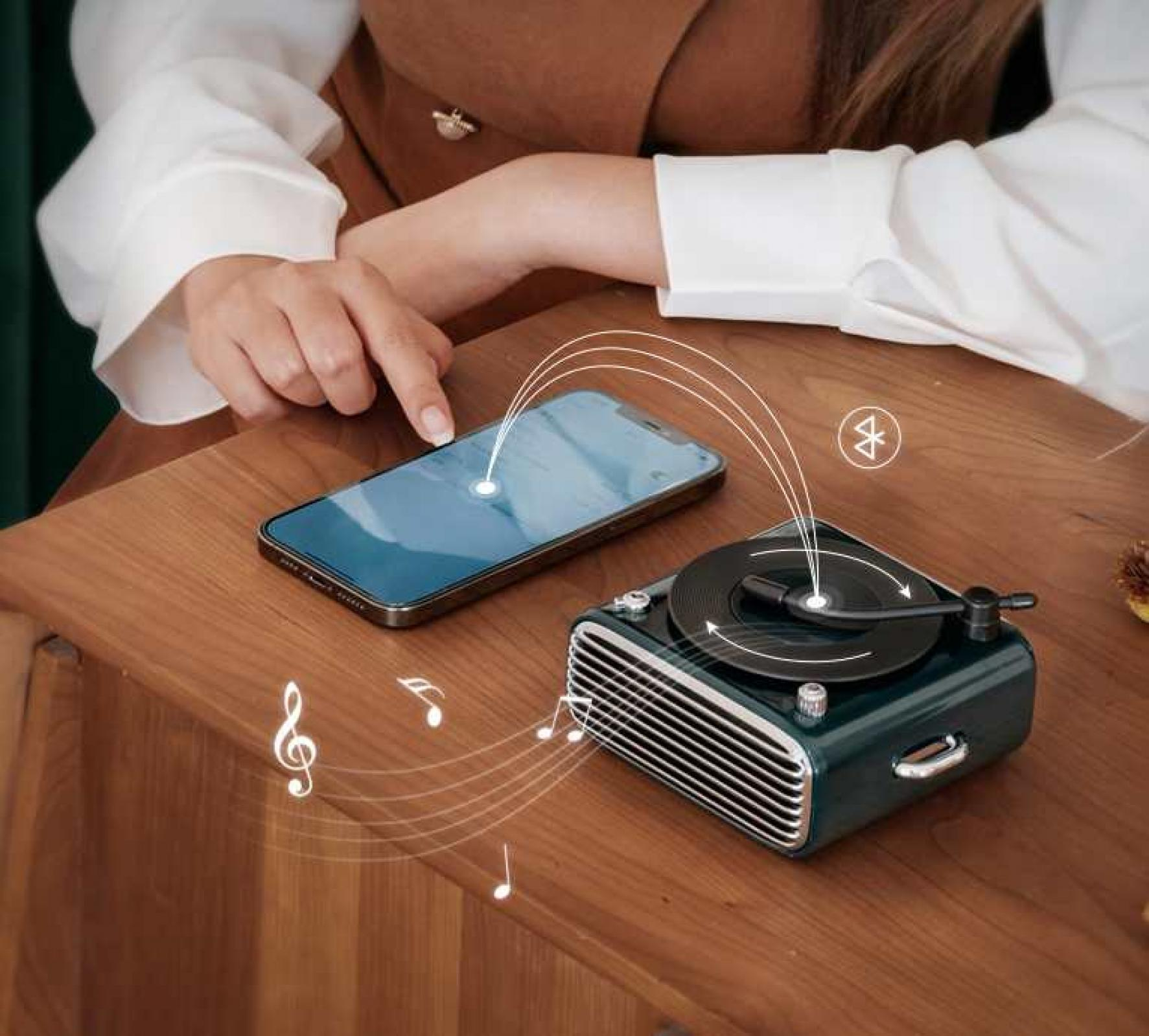 Eine Person benutzt ein Telefon in der Nähe eines Mini-Plattenspielers, mit Noten und einem Bluetooth-Symbol.