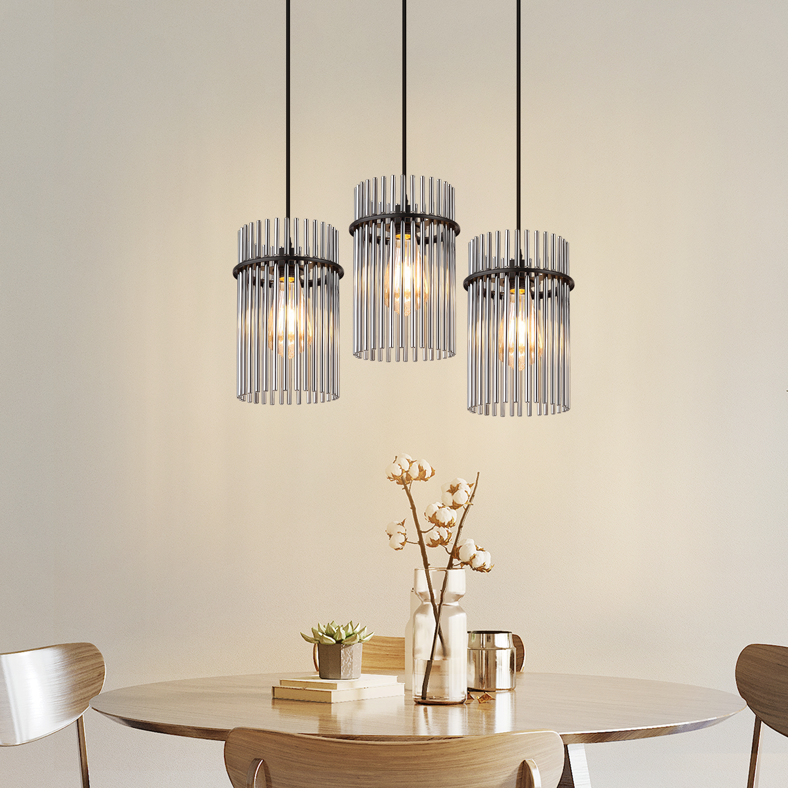 Drei Pendelleuchten mit Glasröhren hängen über einem Tisch mit einem Blumengesteck und einer Sukkulente.