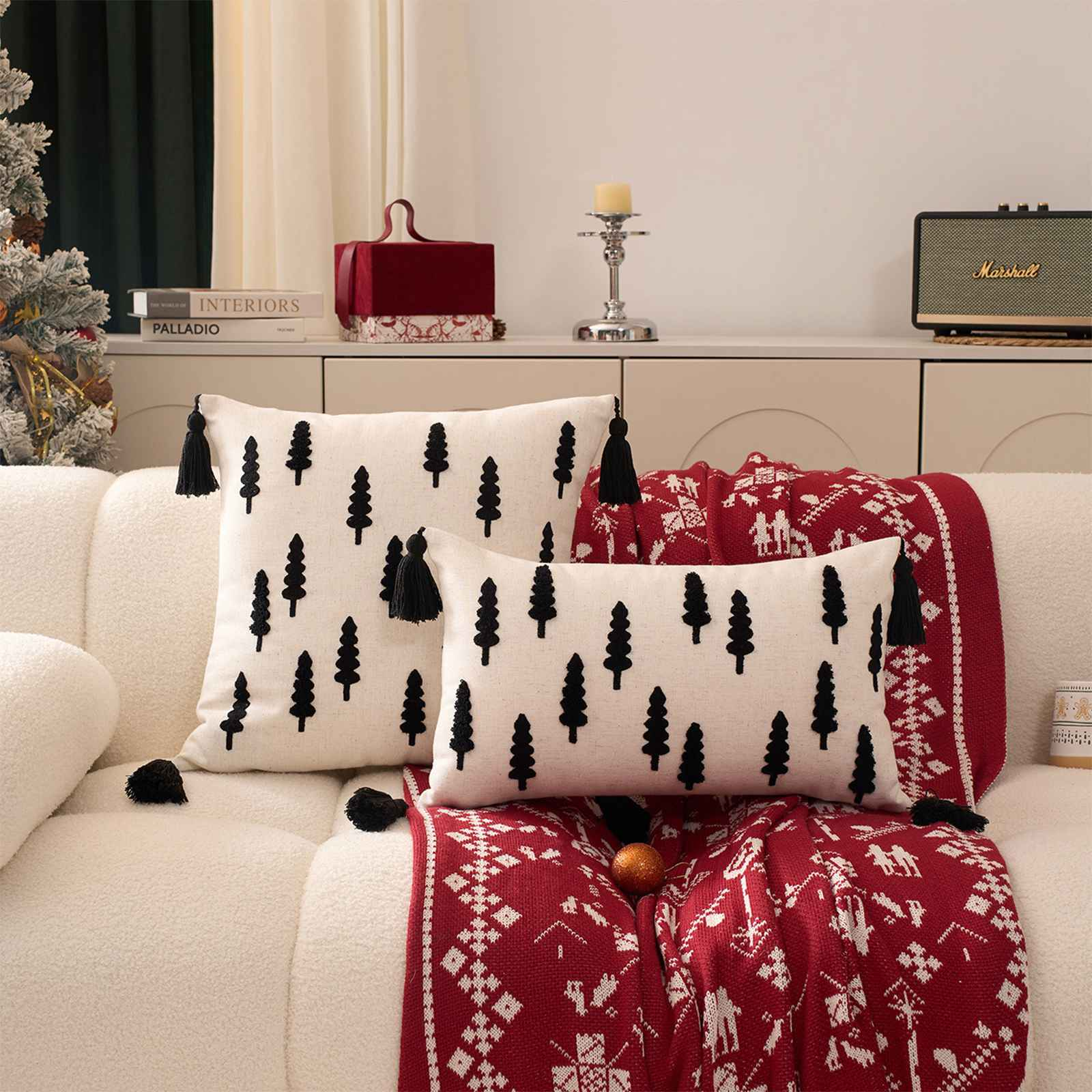 Weißes Sofa mit Kissen, rote Decke. Kissen haben schwarze Baummuster. Im Hintergrund befindet sich ein Marshall-Lautsprecher.