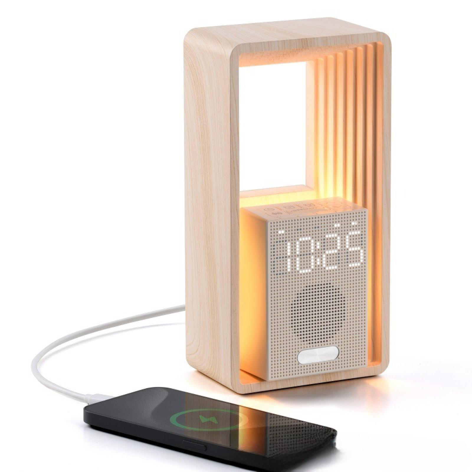 Holzwecker mit Telefonladung. Die Uhr zeigt 10:25. Das Telefon ist schwarz und zeigt ein Ladesymbol.