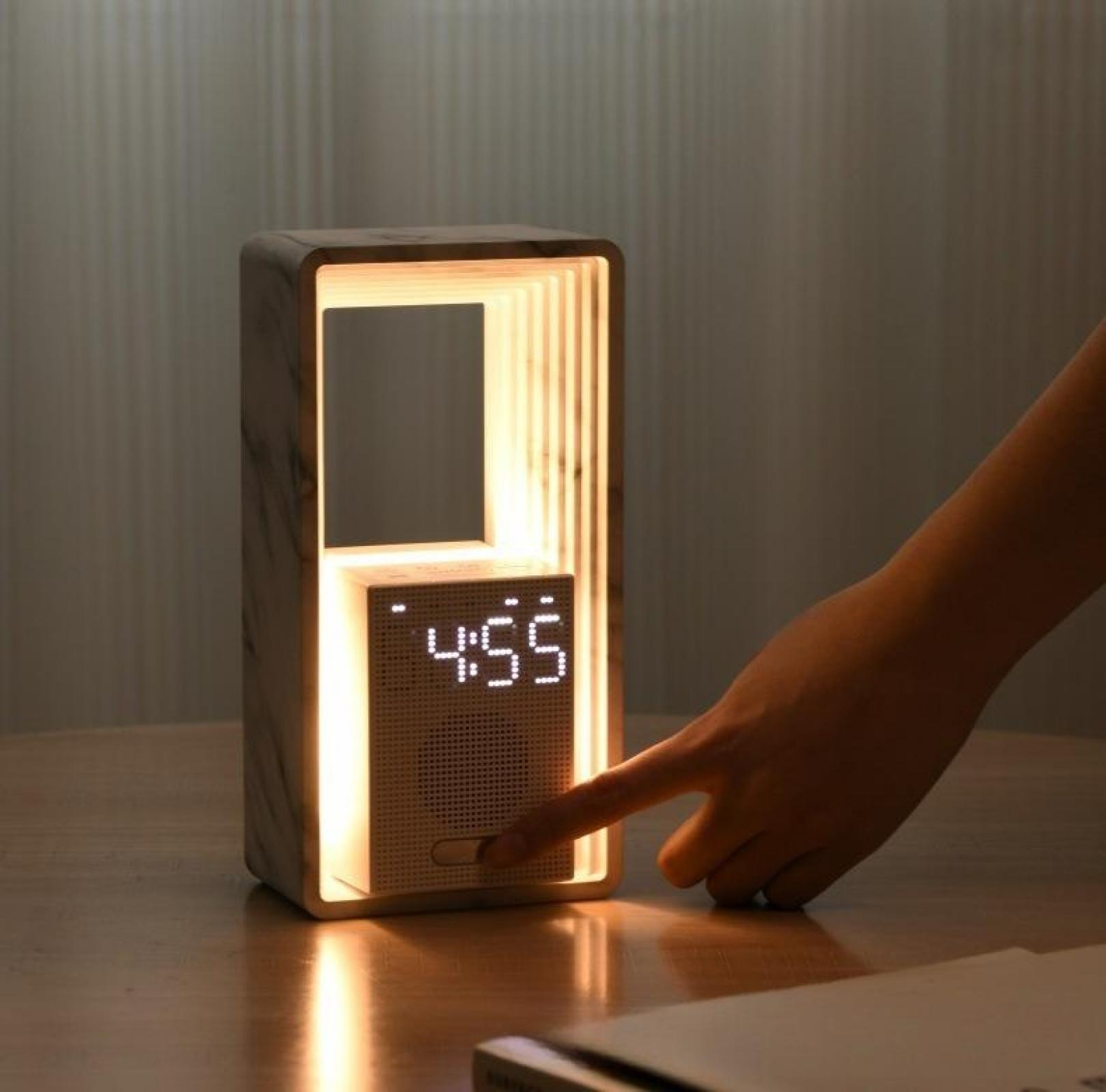 Eine Hand drückt eine Taste auf einer beleuchteten Digitaluhr, die 4:55 anzeigt, in einem Rahmen mit Marmoreffekt. Die Szene ist auf Holz.
