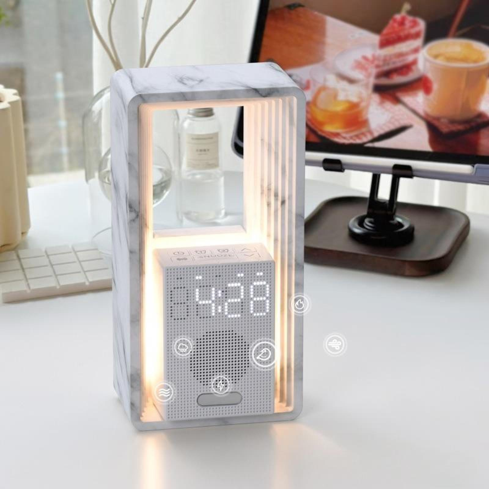 Eine weiße Digitaluhr in einem Marmorrahmen. Im Hintergrund ein Computermonitor und Schreibtischartikel.