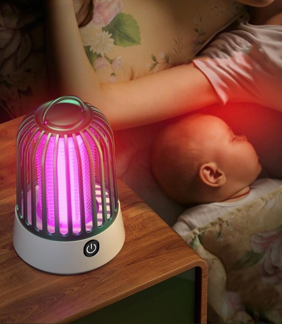 Eine leuchtende Mückenfalle steht auf einem Nachttisch. Ein schlafendes Baby und eine Person sind im Hintergrund, beleuchtet von rotem Licht.