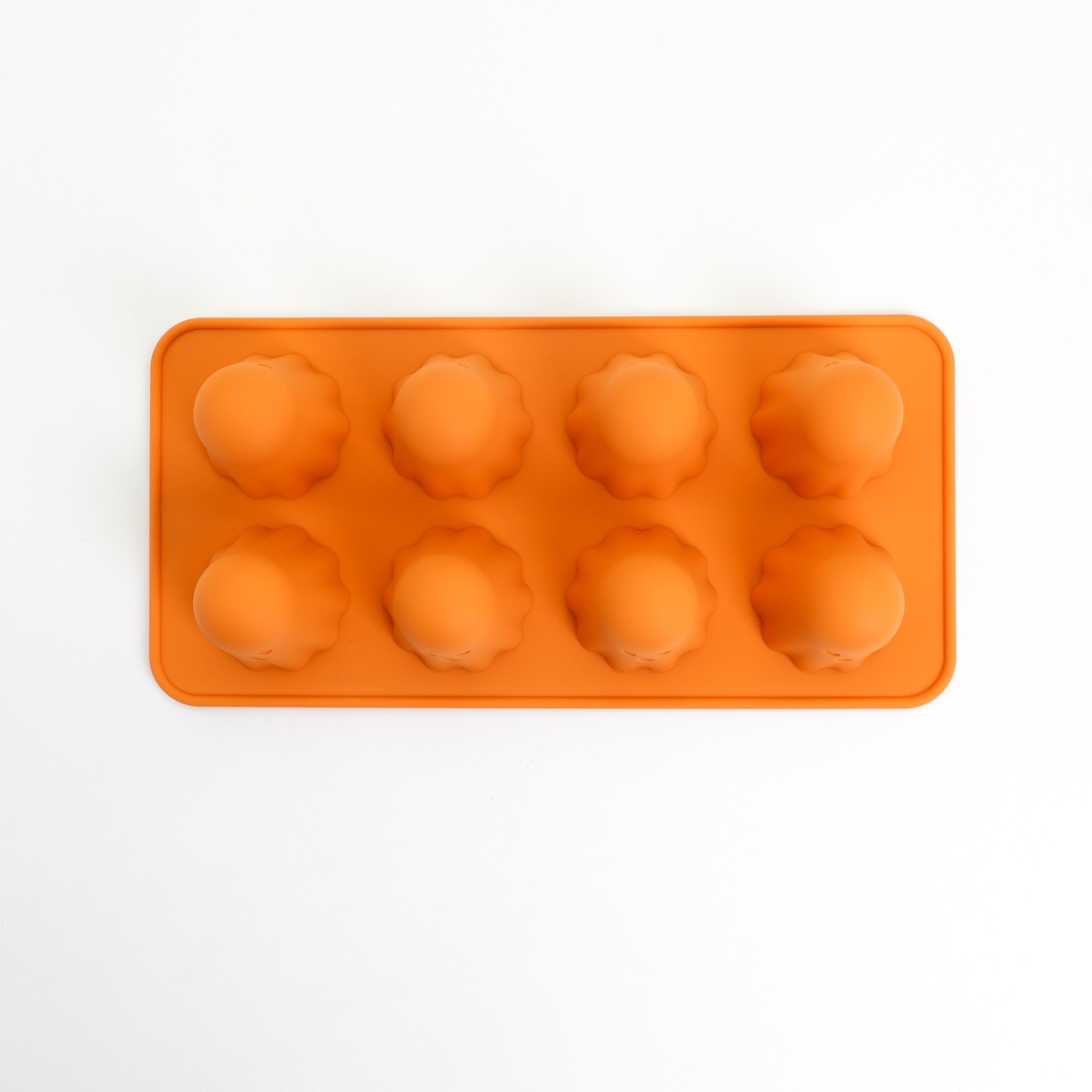 Eine orangefarbene Silikonform mit acht blumenförmigen Hohlräumen auf weißem Hintergrund.