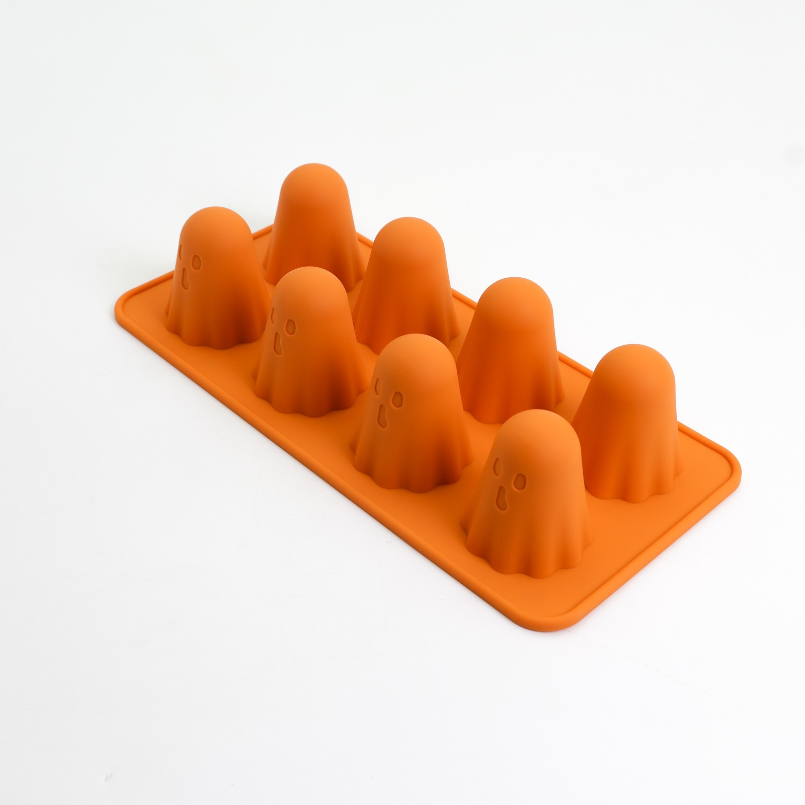 Orangene Silikonform mit acht Geisterformen, jede mit zwei Augenlöchern und einem Mundloch, vor weißem Hintergrund.