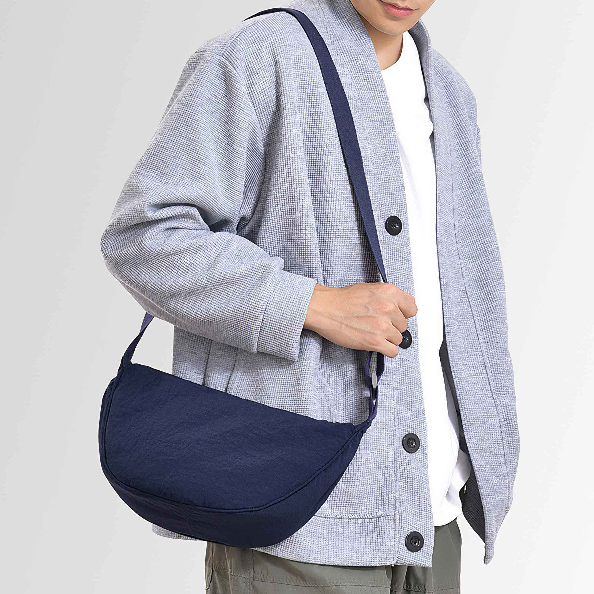 Eine Person mit einer blauen Umhängetasche. Sie trägt eine hellblaue Jacke und ein weißes Hemd.