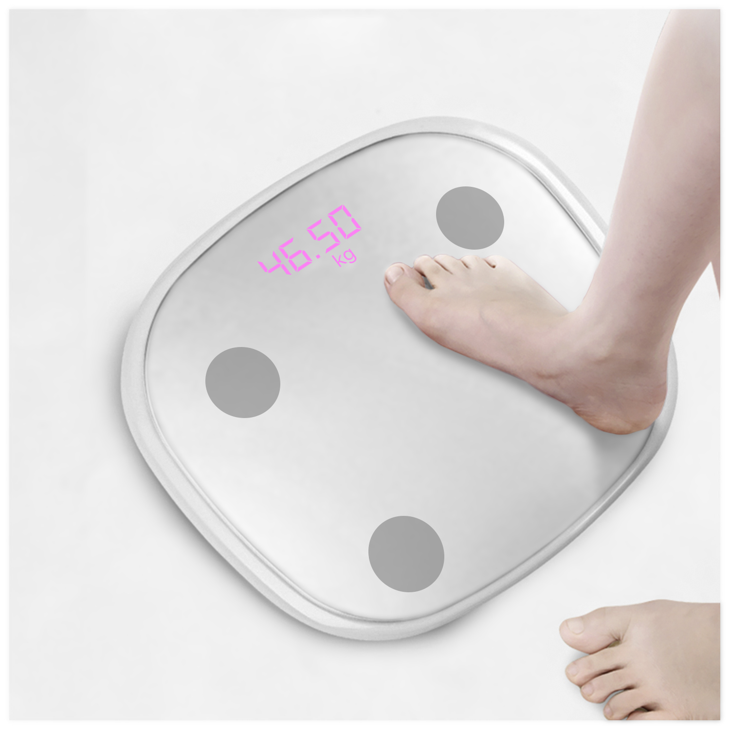 Un pie sobre una báscula digital que muestra 46,50 kg. La báscula es blanca con círculos grises, y se ve otro pie.