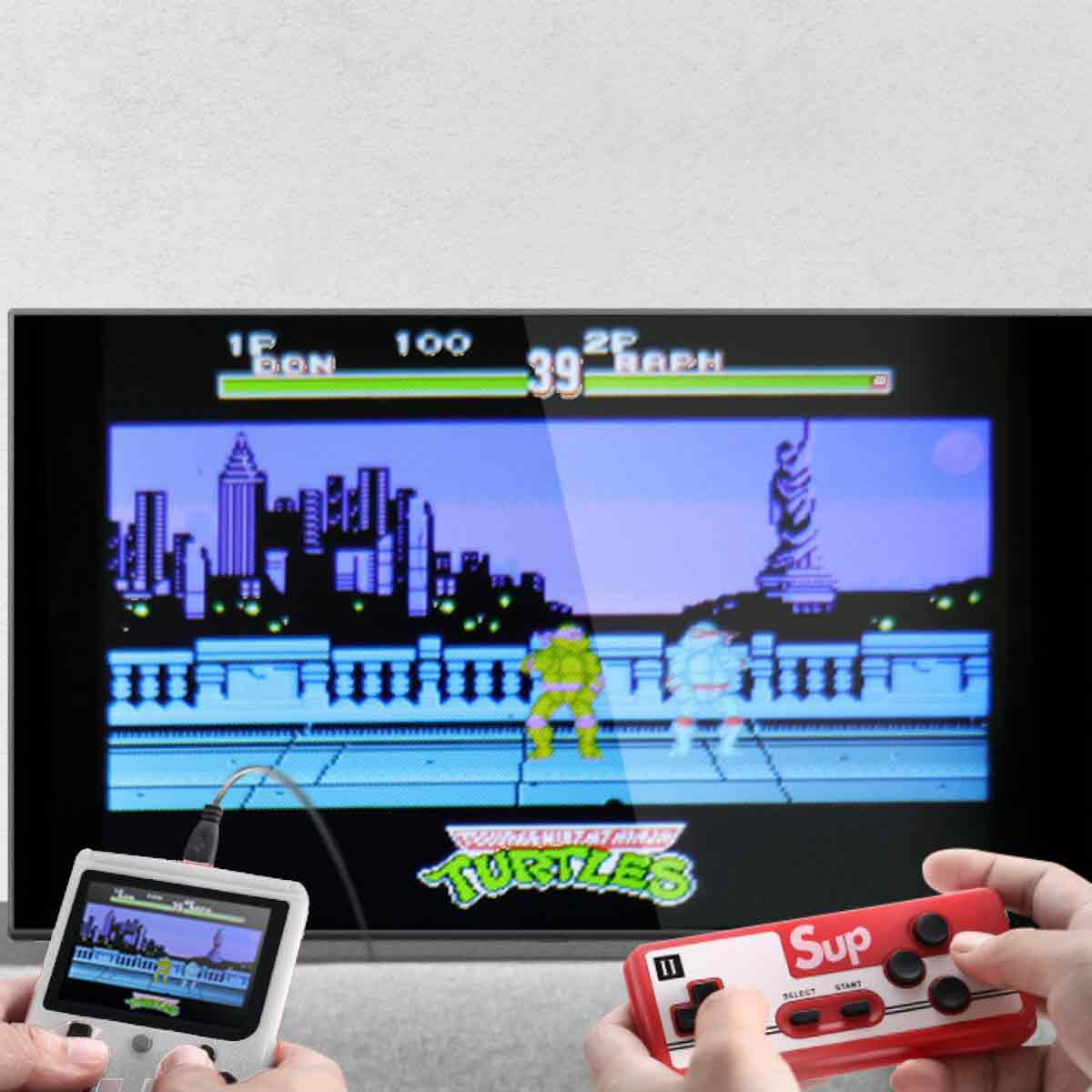 Hände halten Gamecontroller und eine kleine Bildschirm-Spielkonsole, spielen ein Teenage Mutant Ninja Turtles-Spiel auf einem großen Fernsehbildschirm.