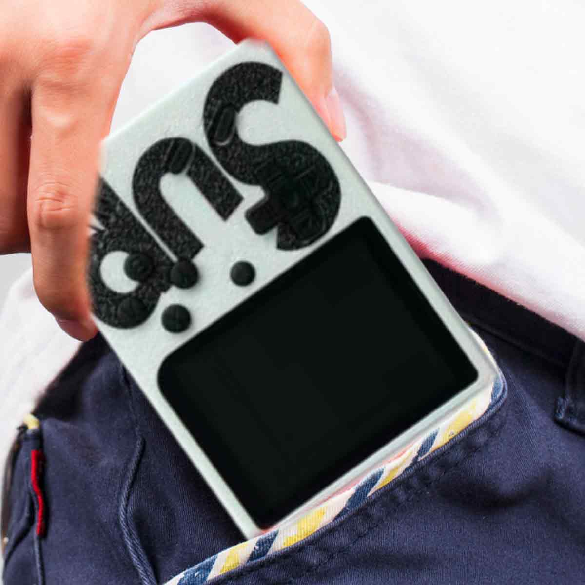 Hand hält eine weiße Retro-Handheld-Konsole mit der Aufschrift 'sup' in Schwarz, teilweise in einer blauen Tasche platziert.