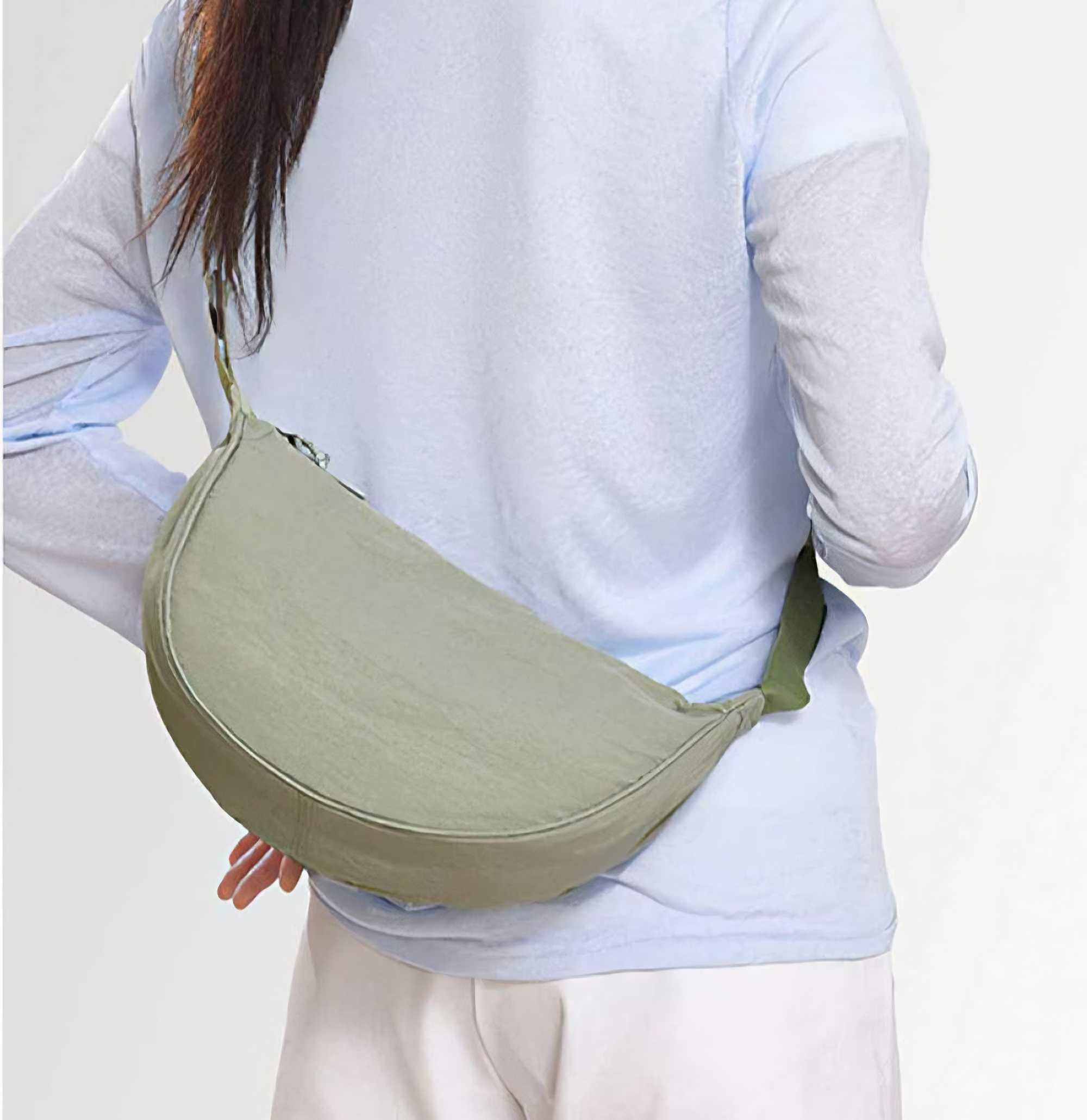 Eine Person mit hellblauem Hemd und weißer Hose, mit einer grünen Tasche über dem Körper.