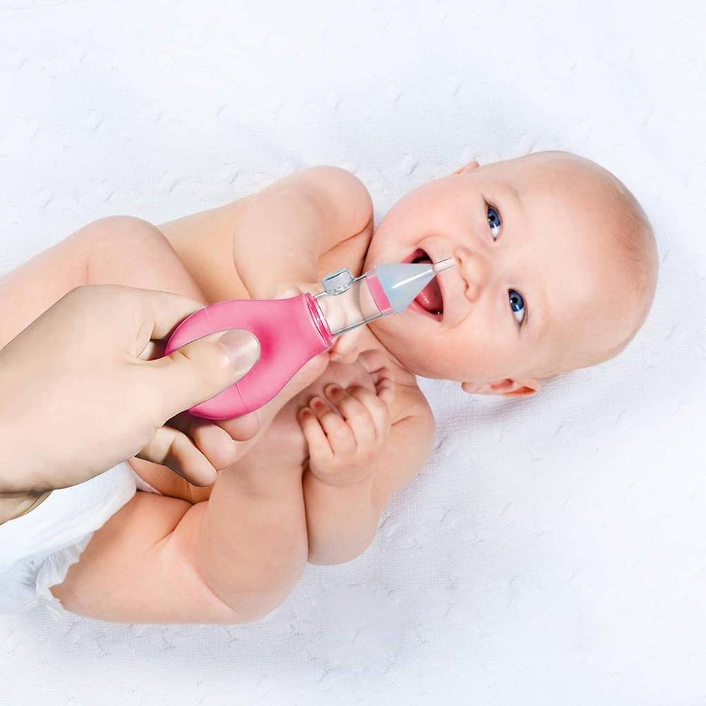 Baby mit blauen Augen hat einen rosa Nasensauger im Mund. Es liegt auf einer weißen Decke. Eine Hand hält den Sauger.