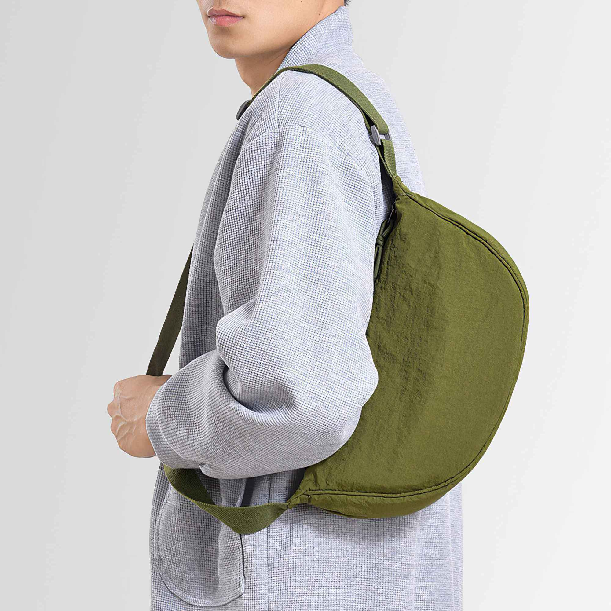 Eine Person mit hellgrauer Jacke und grüner Tasche über der Schulter, weißer Hintergrund.