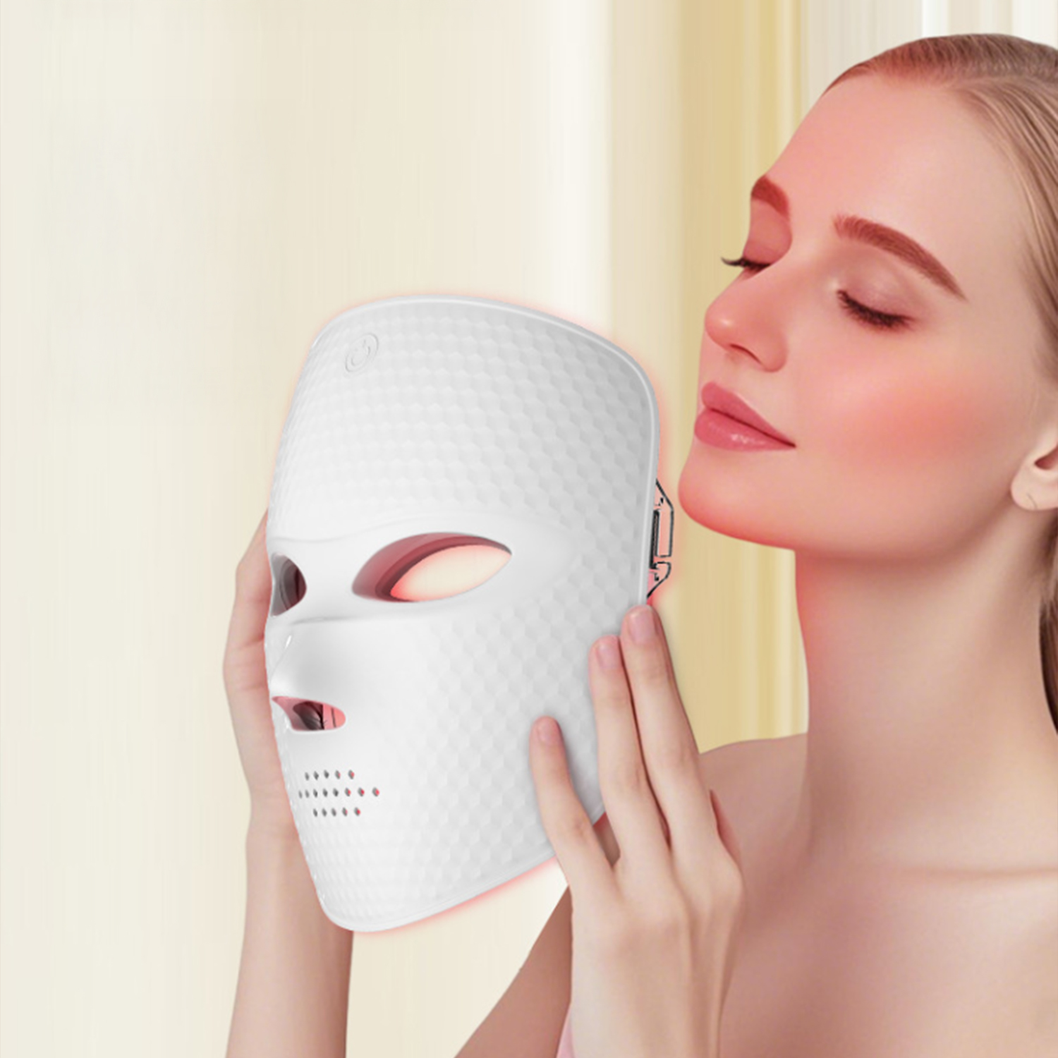 Eine Frau hält eine weiße LED-Gesichtsmaske an ihr Gesicht. Sie hat die Augen geschlossen und ihre Haut leuchtet.