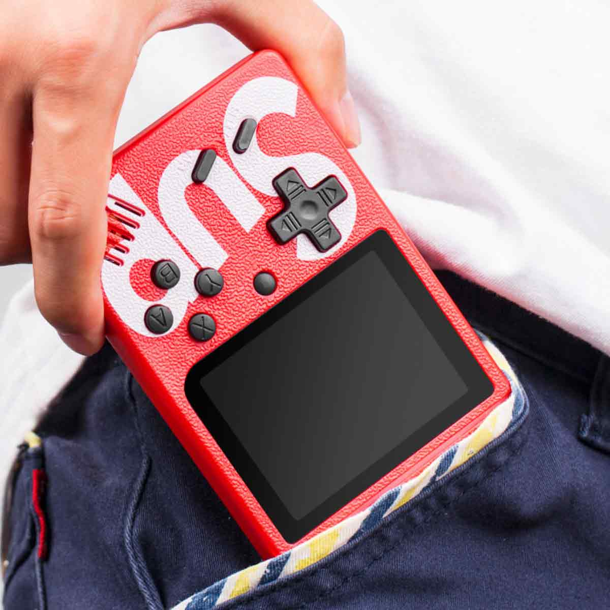 Eine rote SUP-Spielkonsole wird in einer Tasche gehalten. Die Konsole hat weiße Buchstaben und schwarze Knöpfe. Der Hintergrund ist ein weißes Hemd und blaue Jeans.