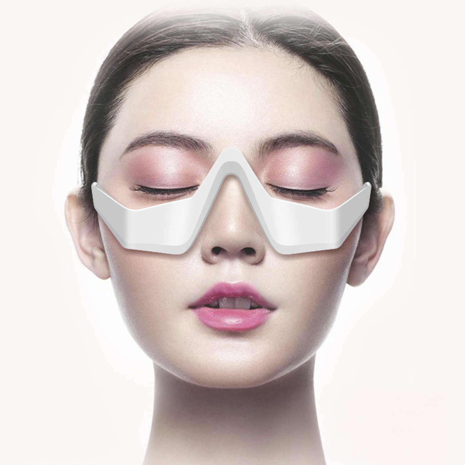 Una donna con gli occhi chiusi indossa una maschera bianca per gli occhi. Sono visibili ombretto rosa e rossetto. Lo sfondo è chiaro.