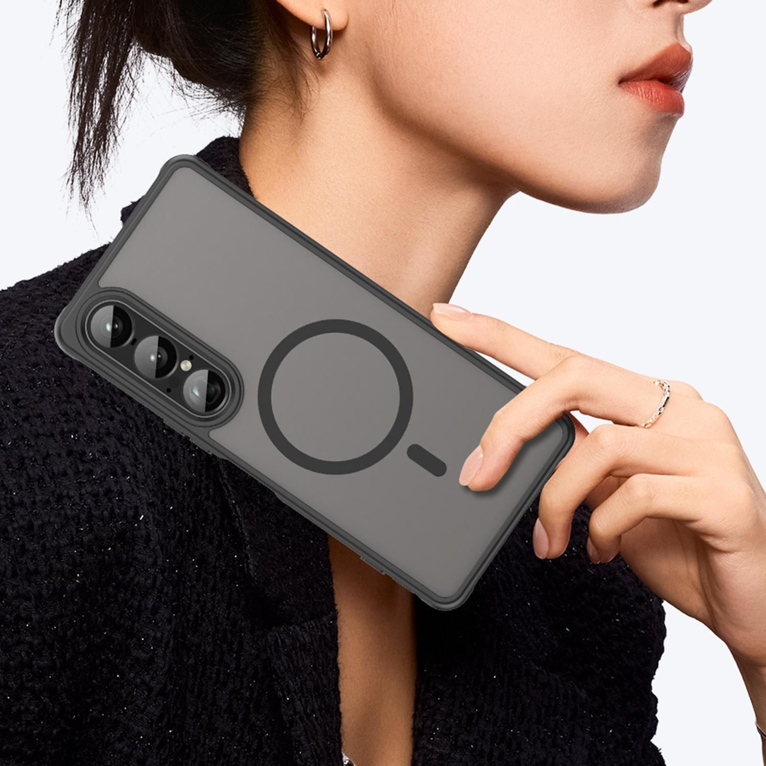 Una mujer sostiene una funda gris para teléfono con un anillo negro. La funda tiene un recorte para la cámara y se sostiene cerca de su rostro.