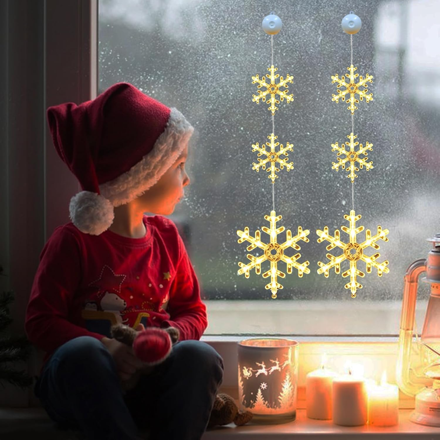 Ein Kind mit Weihnachtsmütze schaut aus einem Fenster mit Schneeflockenlichtern. Kerzen und eine Laterne stehen auf der Fensterbank.