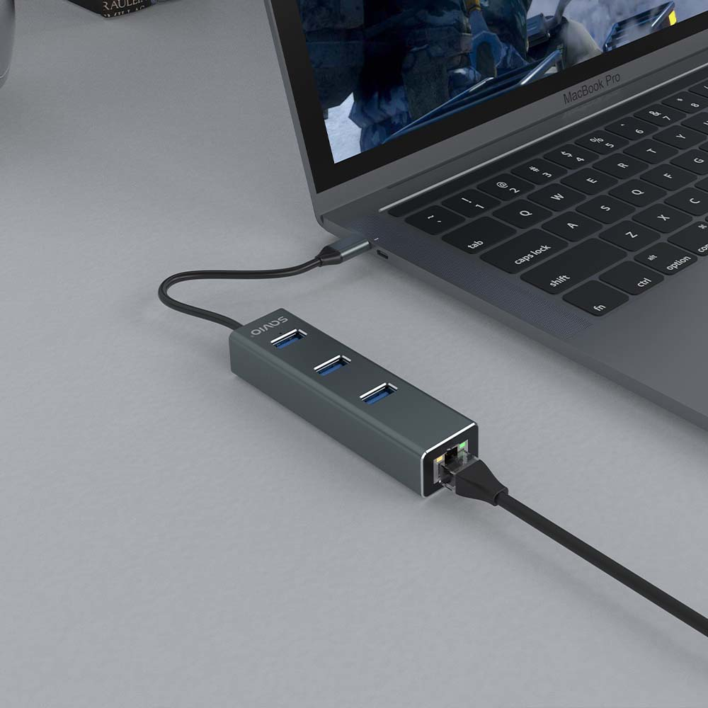 Ein graues MacBook Pro, das mit einem grauen Hub mit USB- und Ethernet-Anschlüssen verbunden ist. Der Hub ist mit dem Laptop verbunden.
