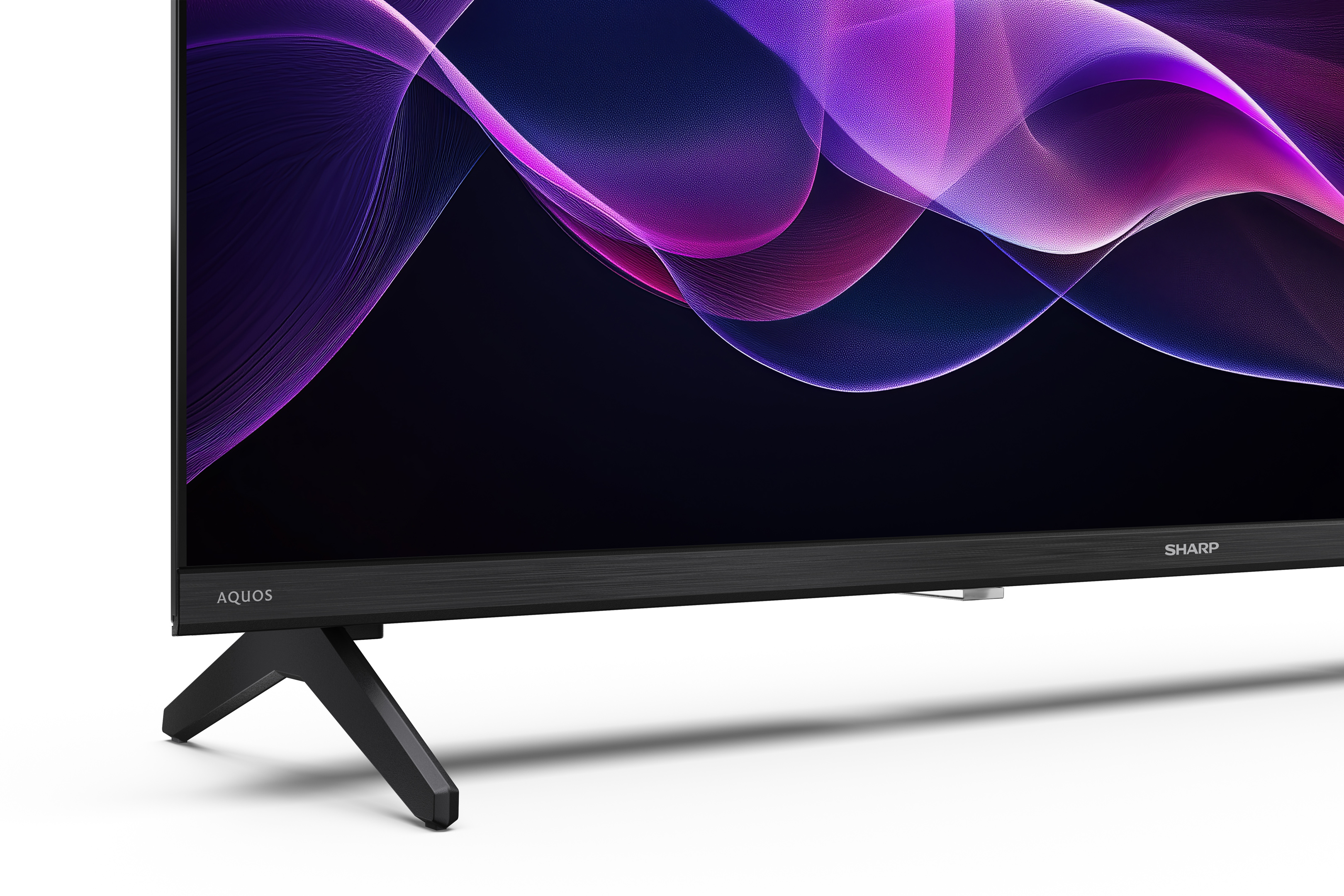 Un téléviseur Sharp Aquos. L'écran affiche un design abstrait violet et rose. Le téléviseur repose sur des pieds noirs.