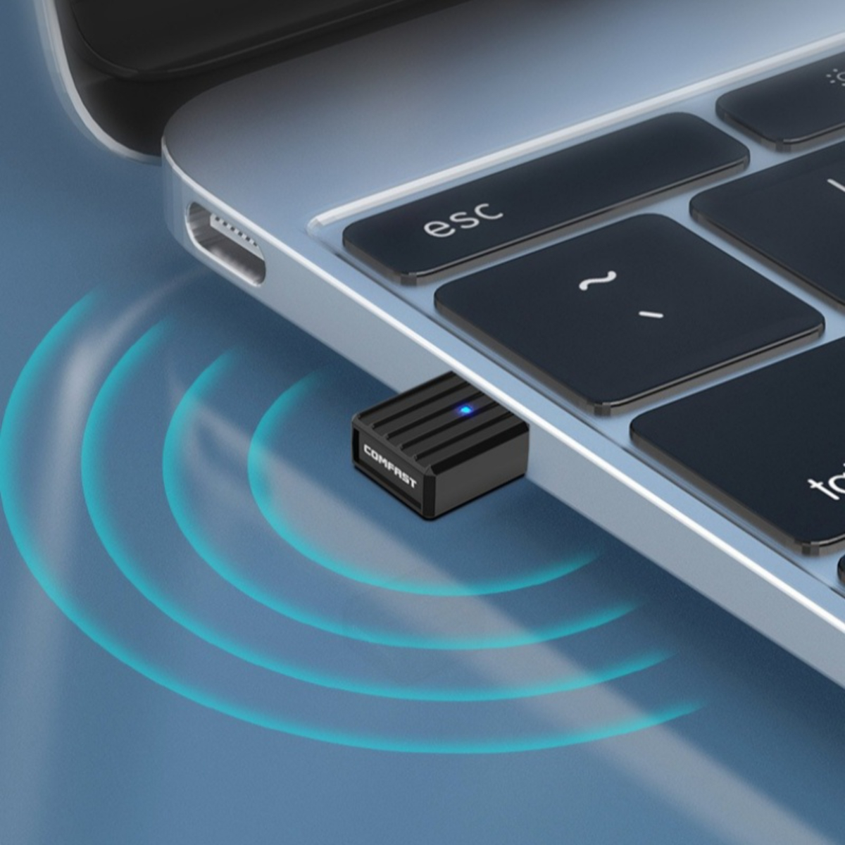 Ein schwarzer USB-Adapter ist an einen Laptop angeschlossen. Der Adapter hat ein blaues Licht und den Markennamen COMPFAST. Blaue Signalwellen sind sichtbar.