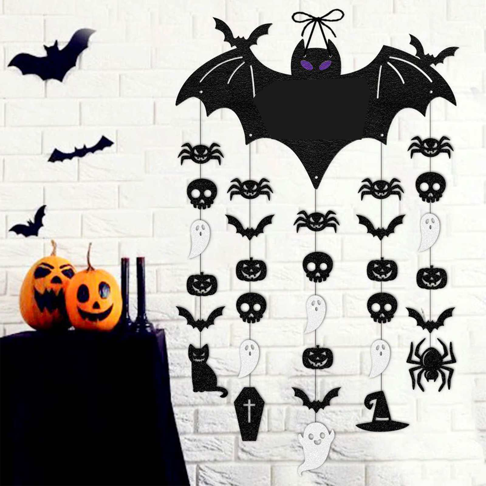 Halloween-Dekorationen: Fledermäuse, Spinnen, Kürbisse, Totenköpfe, Geister und eine schwarze Katze hängen an einer weißen Backsteinmauer.