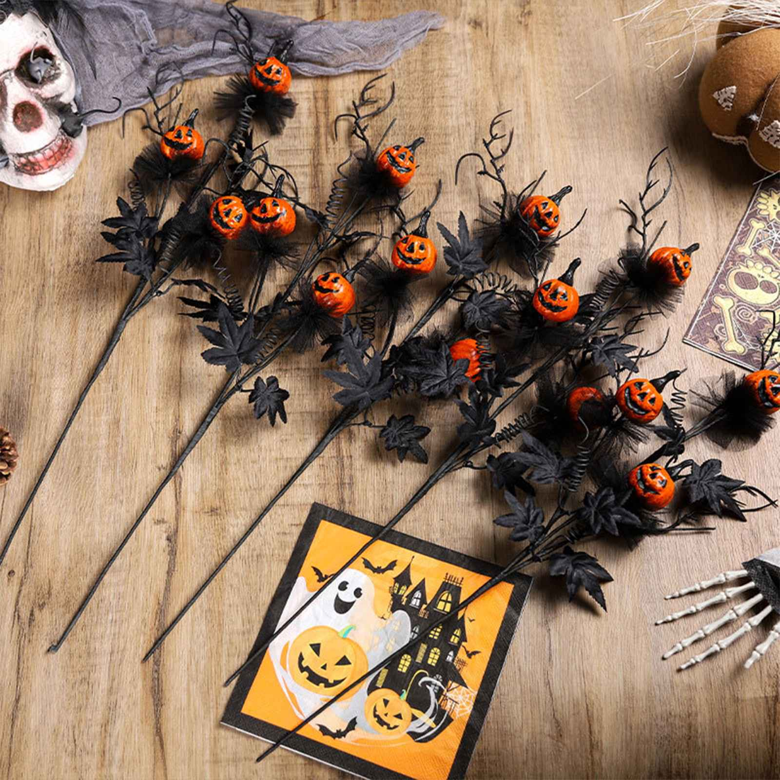 Halloween-Dekorationen: Kürbisstiele, Totenkopf, Serviette mit Geist und Spukhaus, Skeletthand, auf einem Holztisch.
