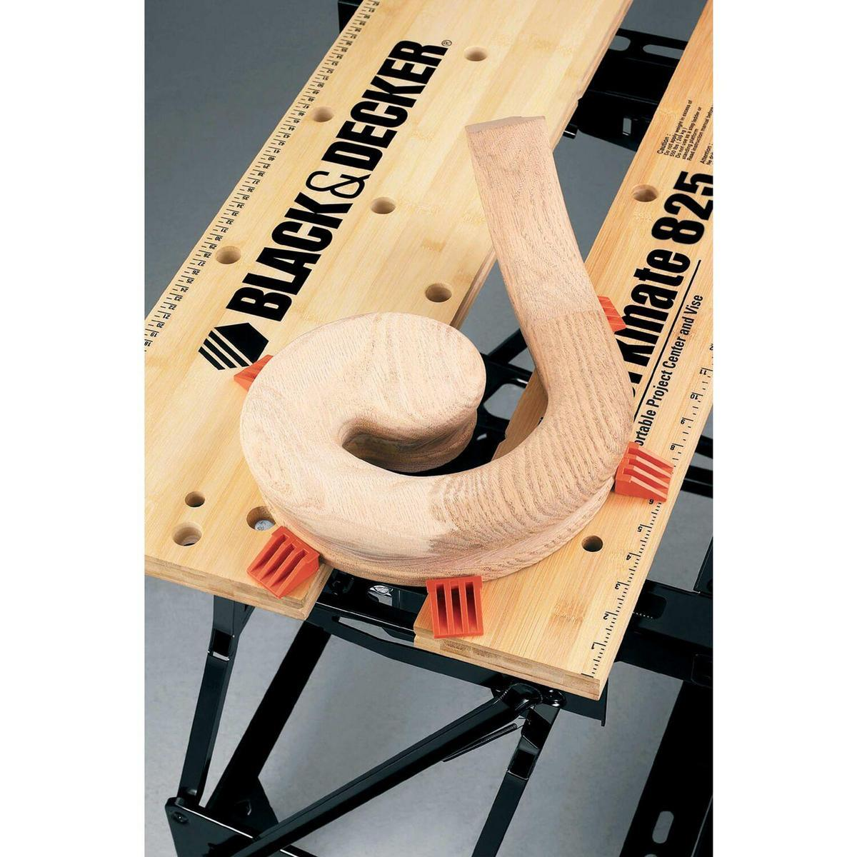 Una pieza de pergamino de madera se sujeta a un banco de trabajo Black & Decker. El banco de trabajo tiene una regla y el nombre de la marca.