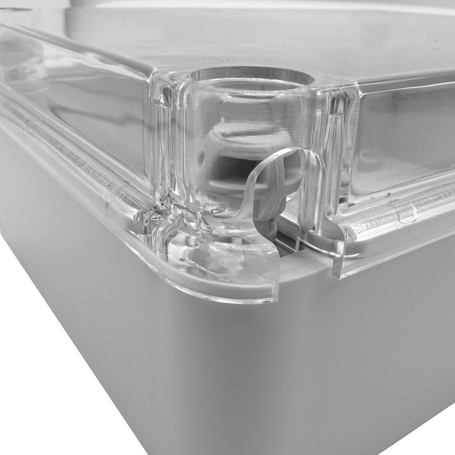 Nahaufnahme einer Ecke einer transparenten Plastikbox mit Deckeldetail und Verschlussmechanismus. Die Box ist grau, der Hintergrund weiß.