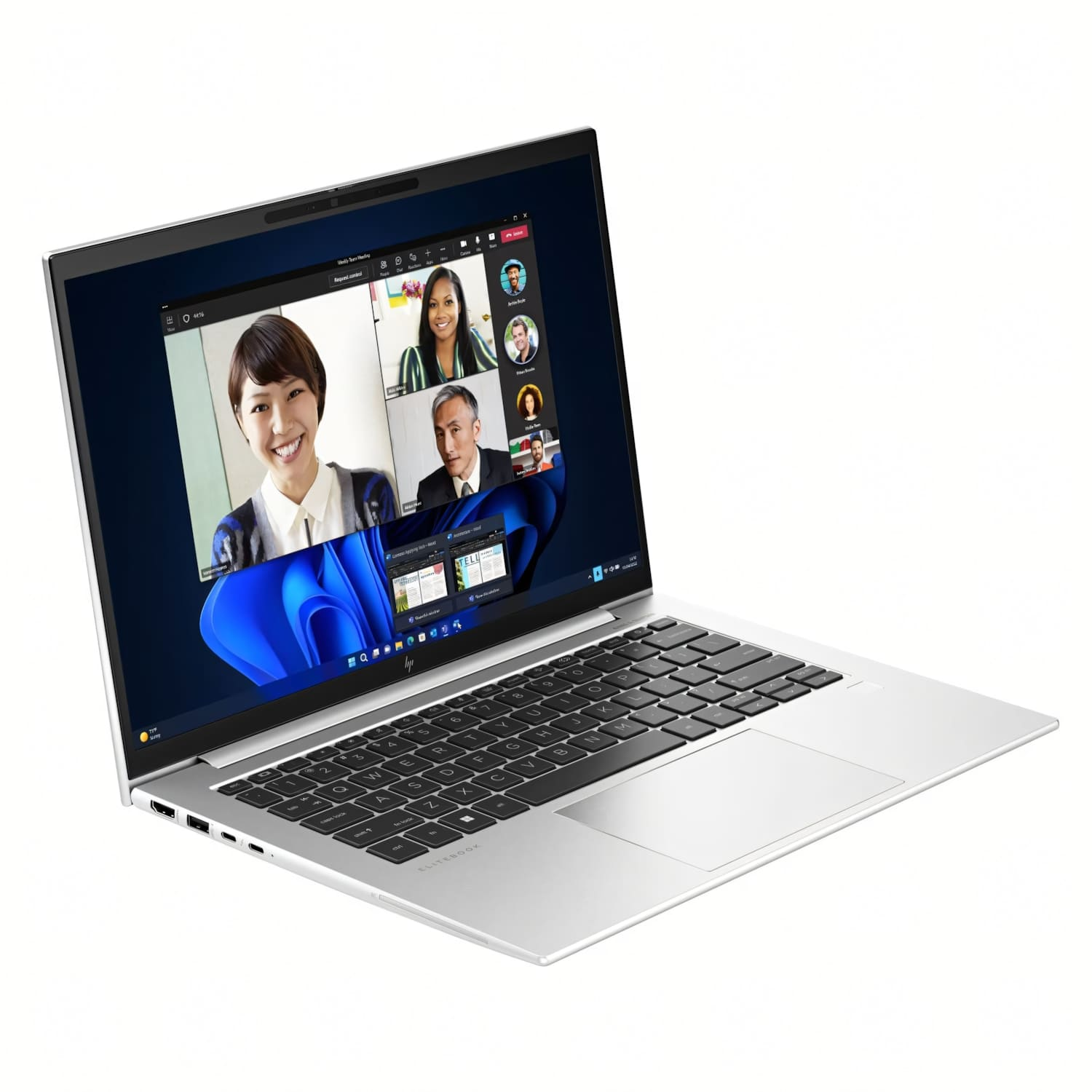 Portátil plateado muestra una videollamada con cuatro personas. La pantalla muestra una interfaz de Windows. El teclado es negro.