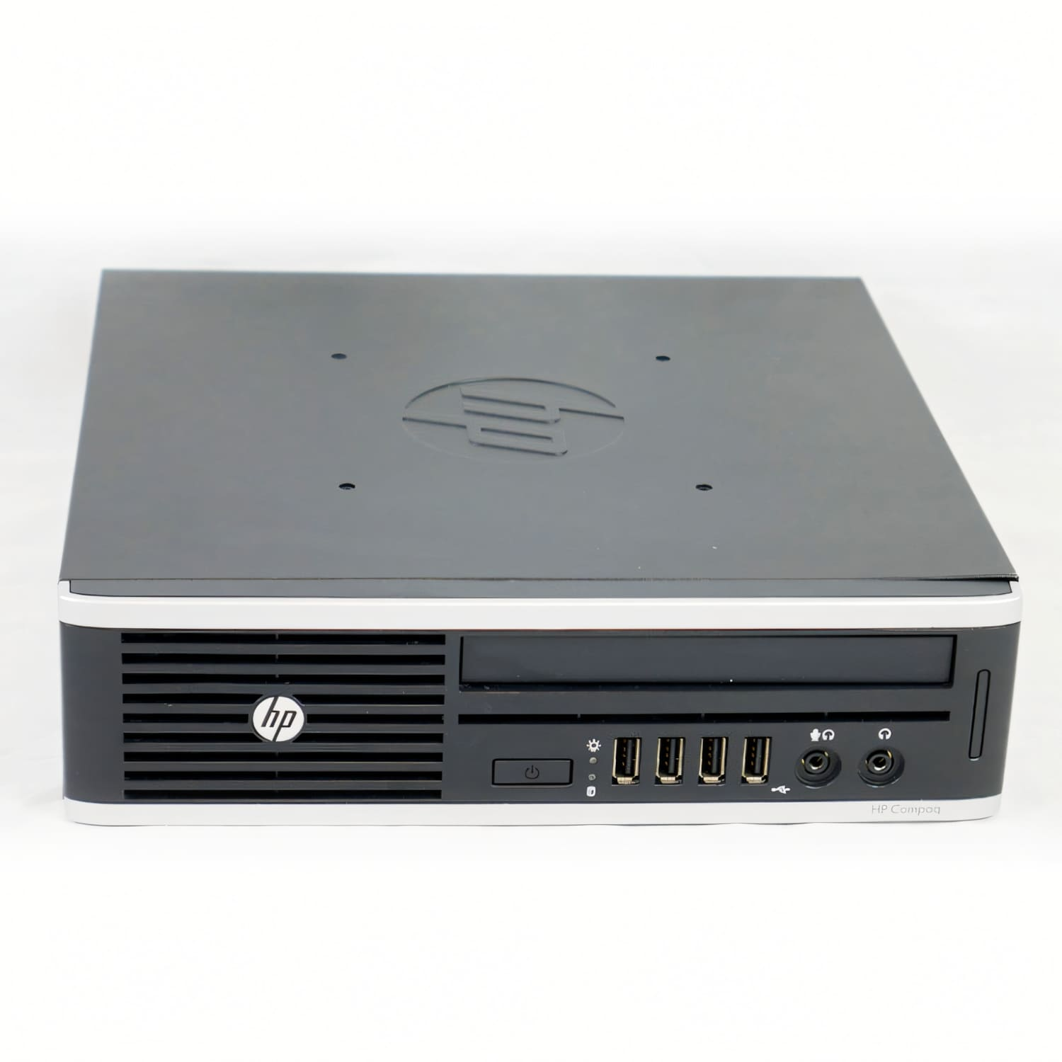 Una computadora de escritorio HP Compaq. Es negro y gris con el logotipo de HP en la parte delantera. Se asienta sobre una superficie blanca.