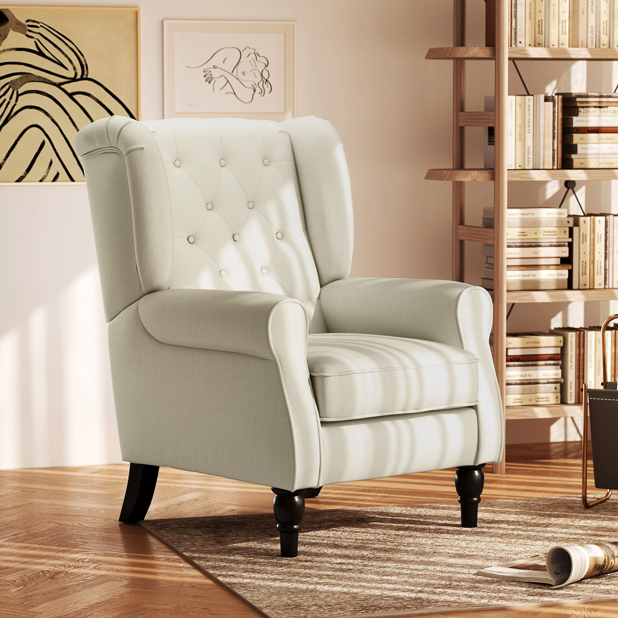 Poltrona color crema con gambe nere, in una stanza con libreria e arte.