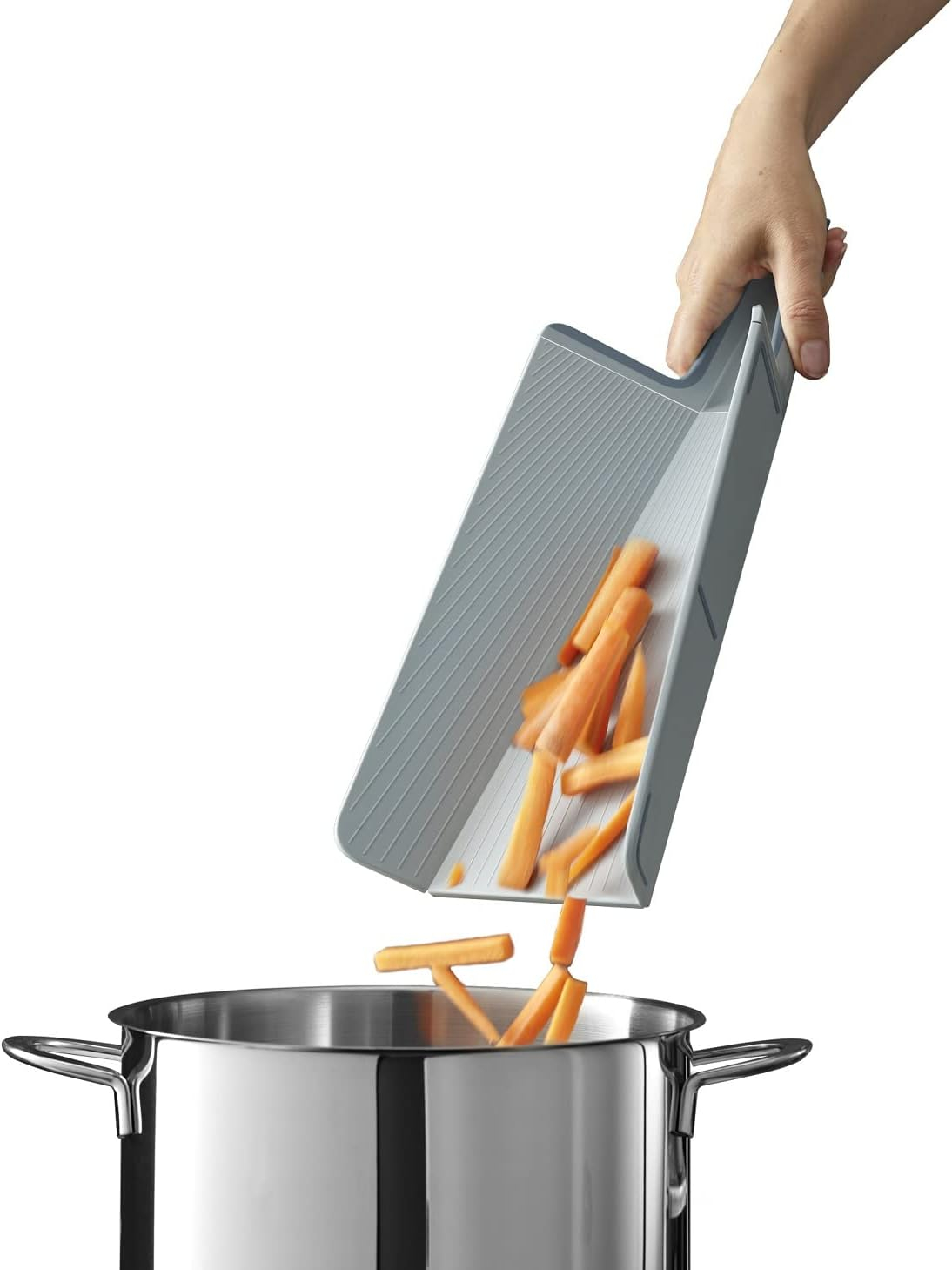 Eine Hand schüttet Karottensticks von einem grauen Schneidebrett in einen Edelstahltopf.