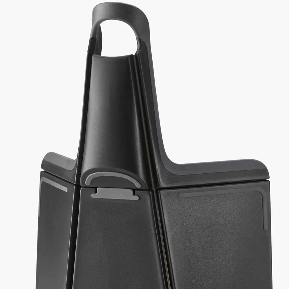 Primer plano de un objeto negro estructurado con asa. El objeto tiene una base rectangular y una parte superior curva.