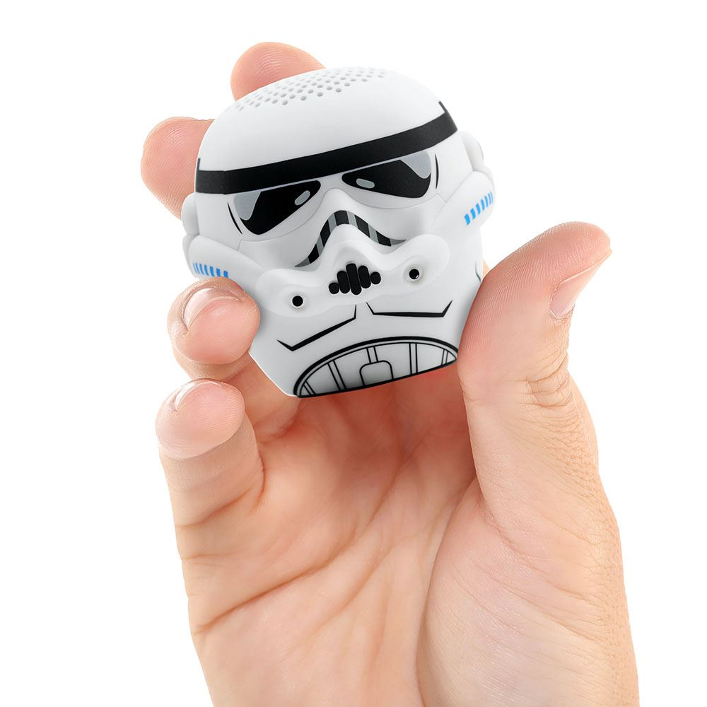 Una mano tiene in mano un altoparlante a forma di casco da Stormtrooper bianco. Ha dettagli neri e accenti blu. Lo sfondo è bianco.