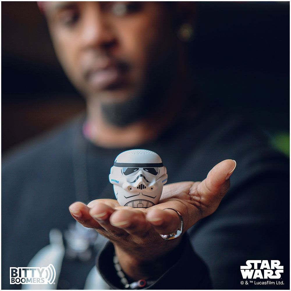Una persona tiene in mano un altoparlante a forma di Stormtrooper. L'altoparlante è bianco con dettagli neri. La persona è sfocata.