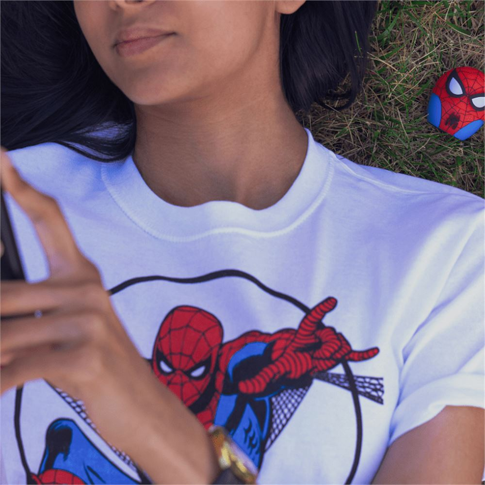 Una persona con una maglietta di Spider-Man è sdraiata sull'erba, tenendo un telefono. Un giocattolo di Spider-Man è vicino.