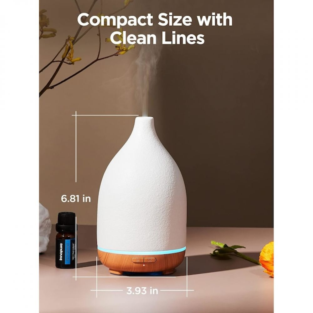 Weißer Diffusor für ätherische Öle mit Holzsockel, Maße angegeben. Eine Ölflasche und aufsteigender Dampf sind ebenfalls zu sehen.