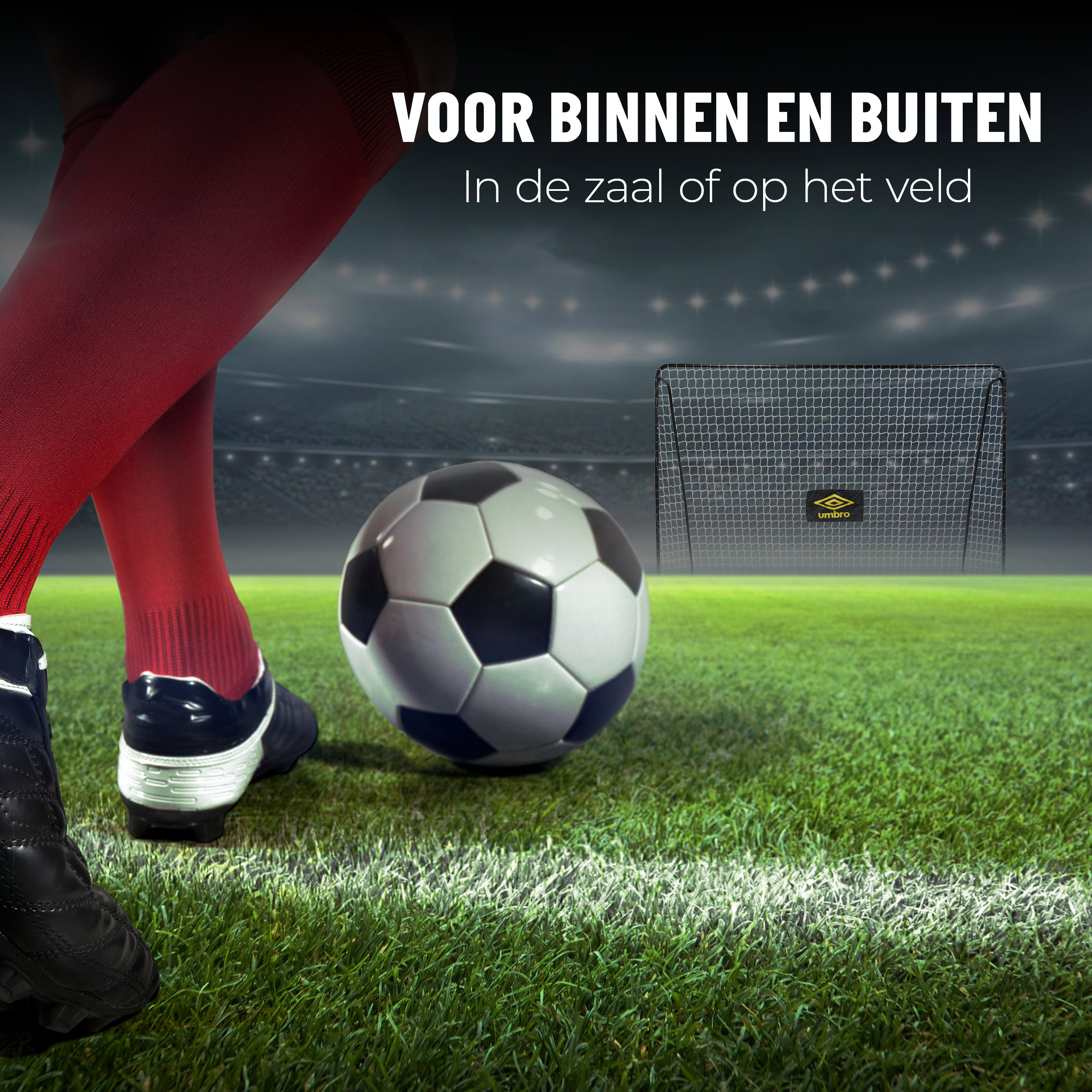 Voetbal op grasveld bij doel. Benen en voeten van voetballer zichtbaar. Stadion achtergrond.