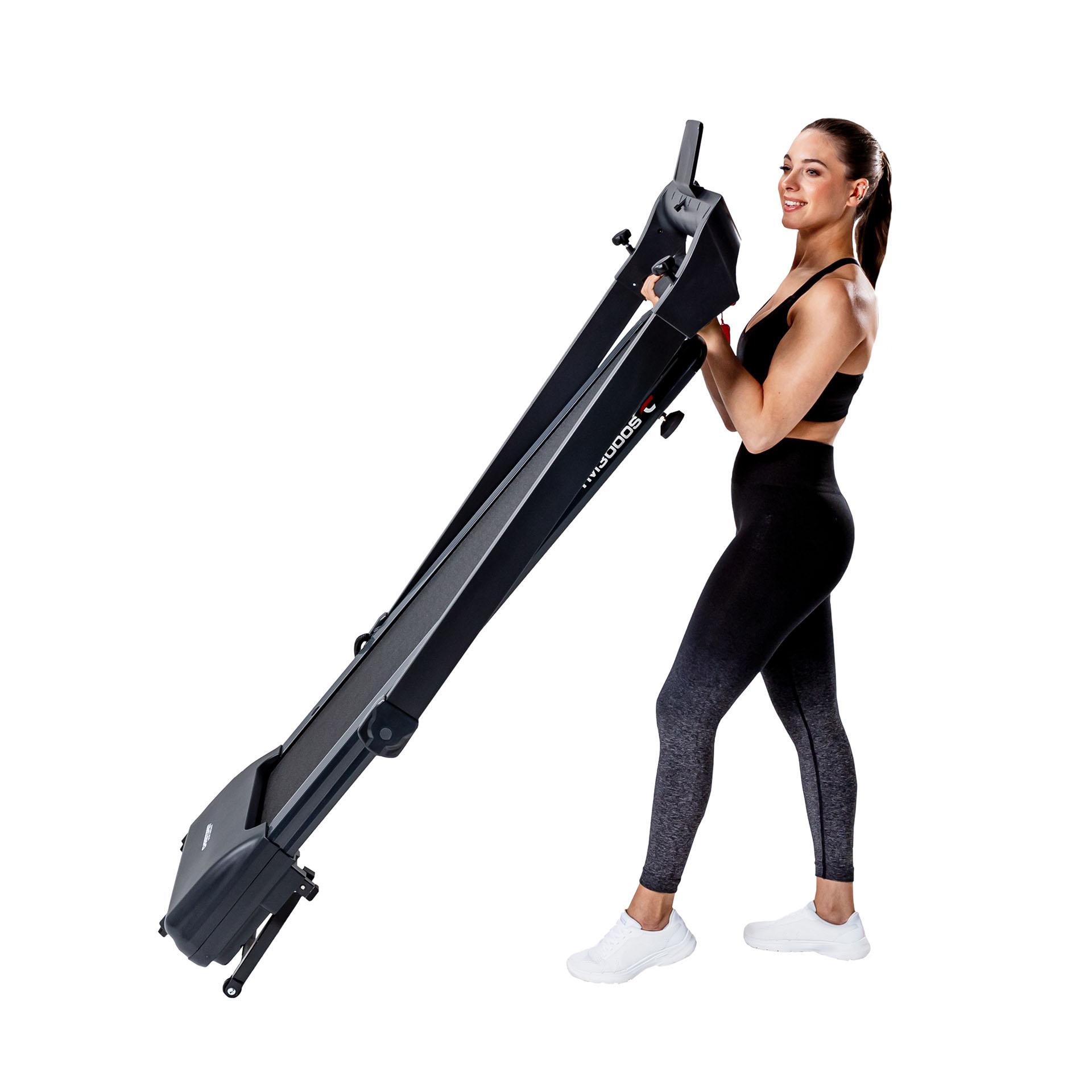 Eine Frau hält ein schwarzes Laufband. Sie trägt einen schwarzen Sport-BH, Leggings und weiße Turnschuhe.