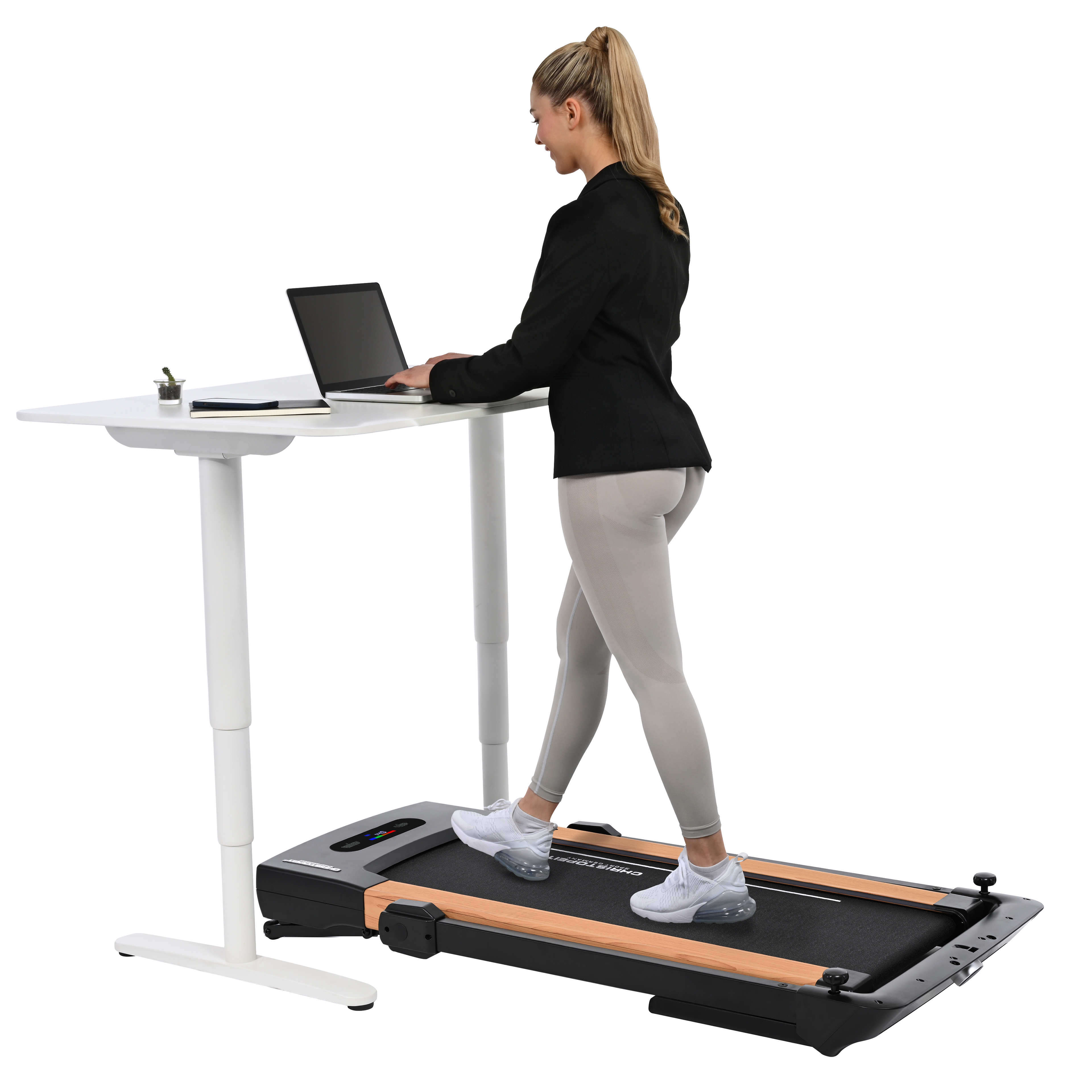 Eine Frau in Businesskleidung geht auf einem Laufband, während sie an einem Laptop an einem Stehpult arbeitet.