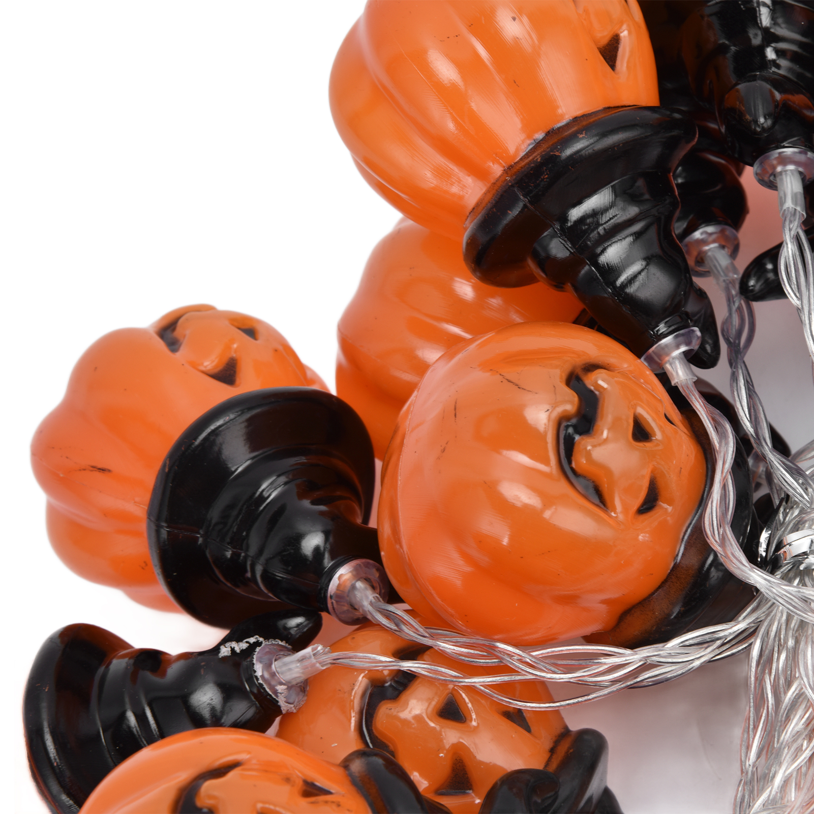 Nahaufnahme von Halloween-Kürbislichtern. Orangefarbene Kürbisse mit schwarzen Sockeln und Gesichtern. Silberne Drähte auf weißem Hintergrund.